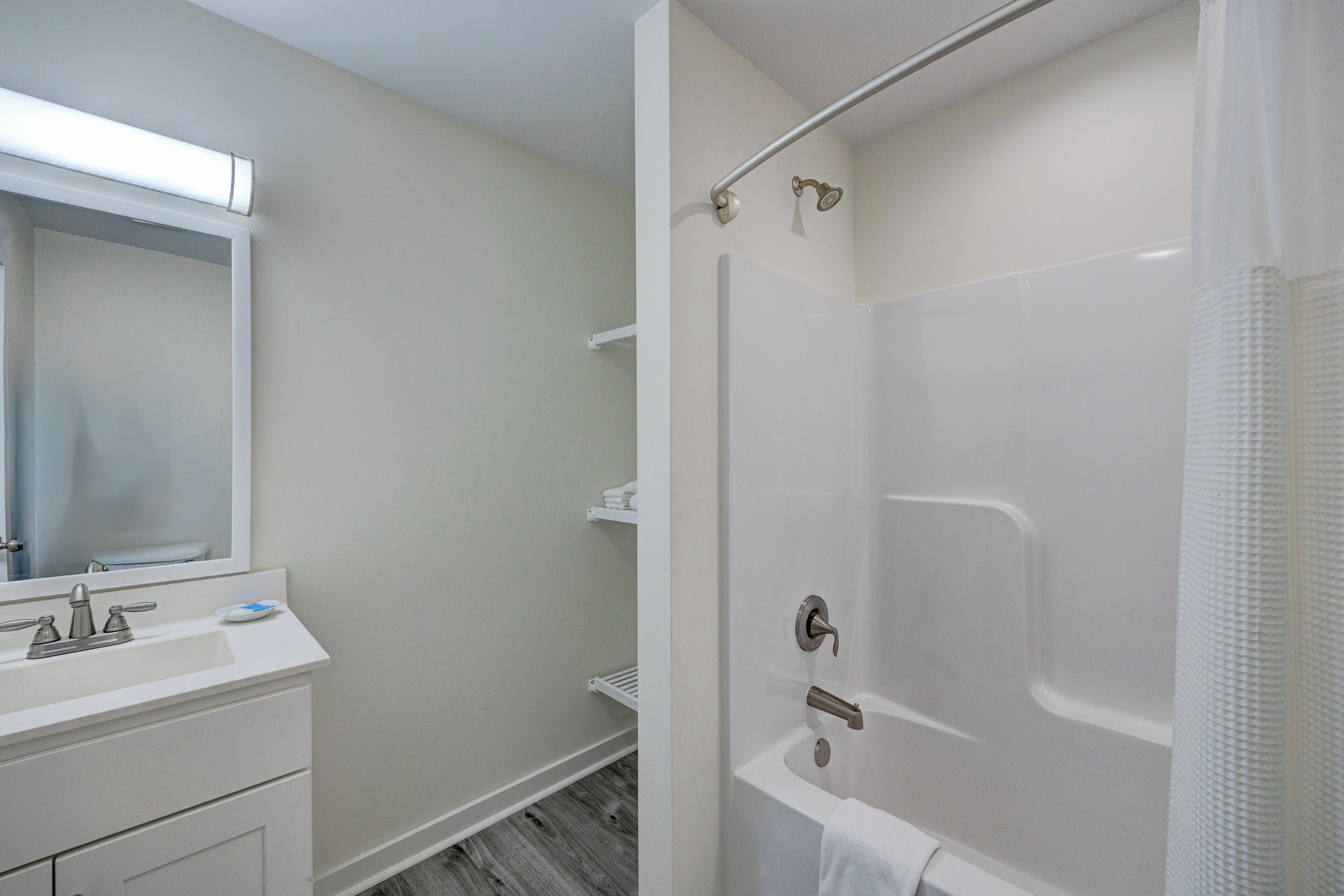 A modern bathroom with a white sink, mirror, and shower.