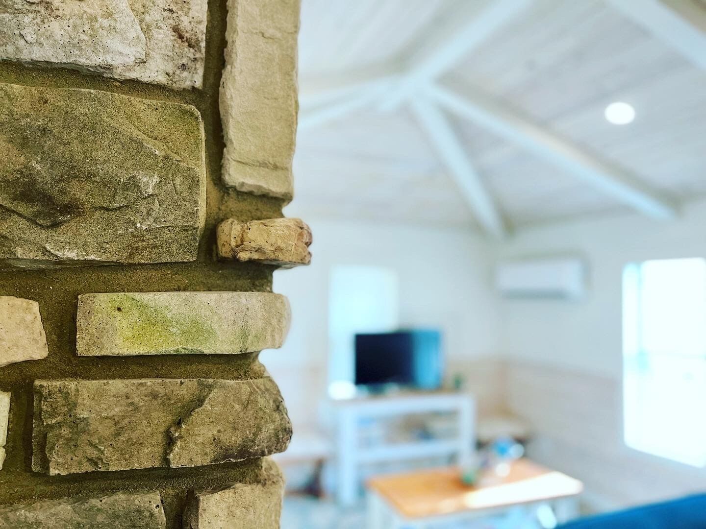 A stone wall in a room with a television and a table.