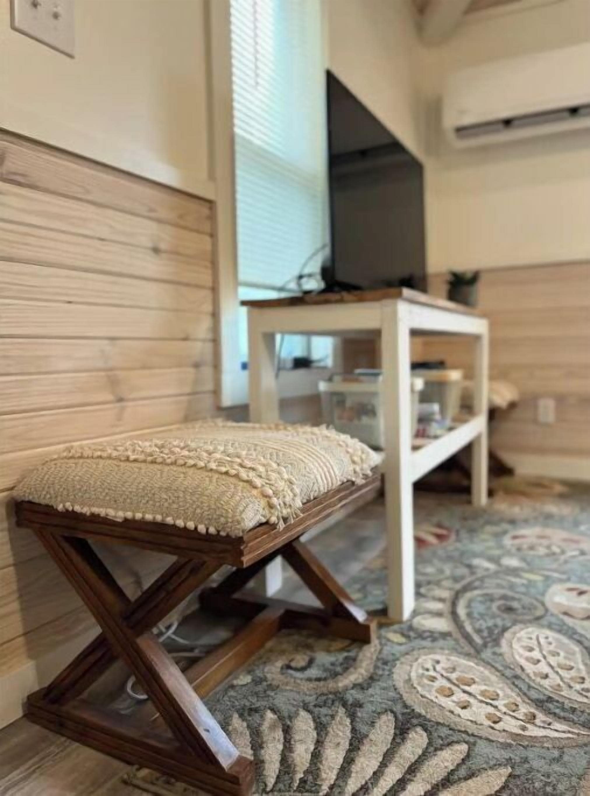 A wooden bench with a cushion, a white shelf unit, and a patterned carpet in a room with wooden paneling.
