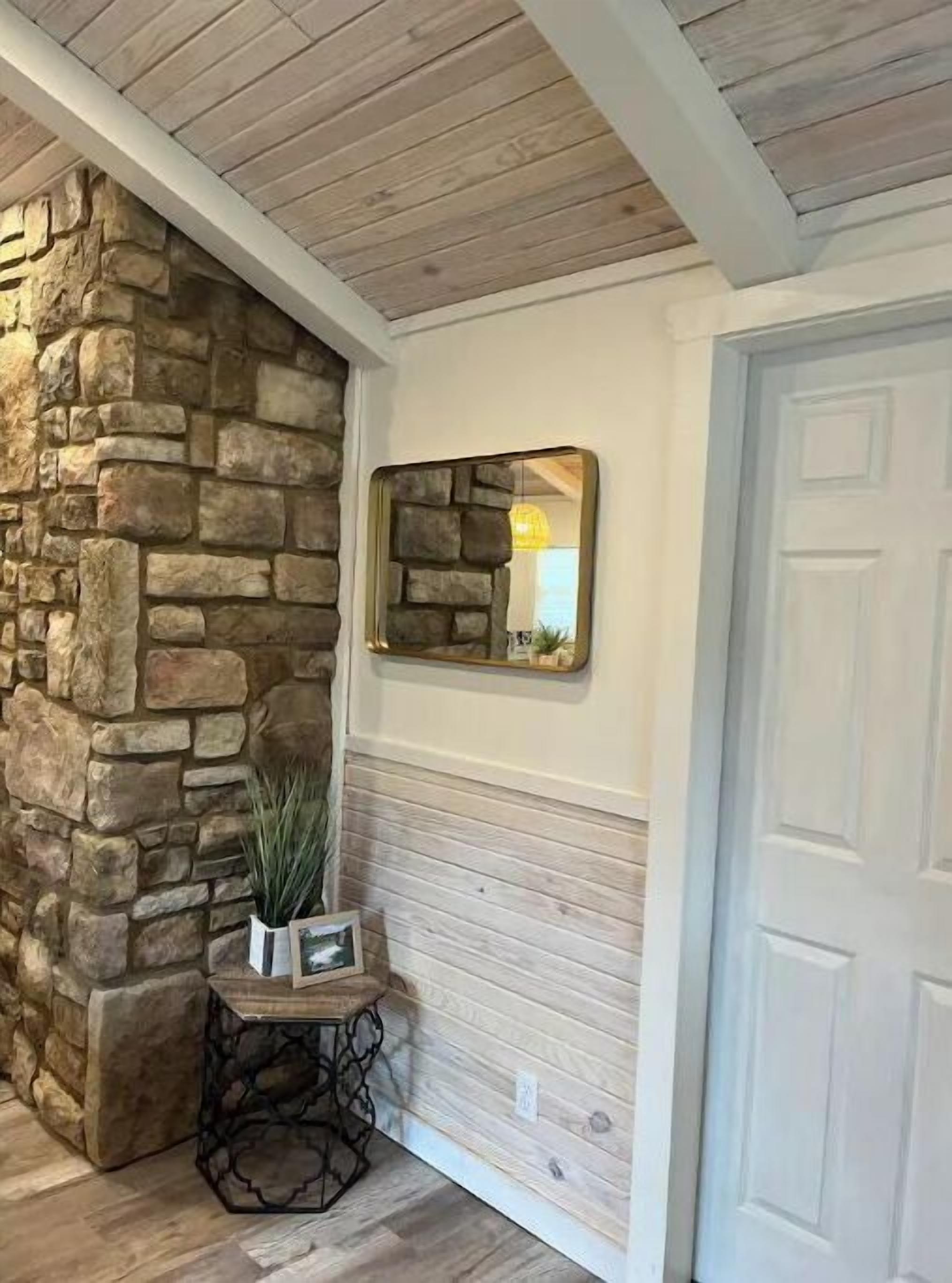Un muro de piedra, una puerta de madera y un cuadro en un pequeño escritorio.