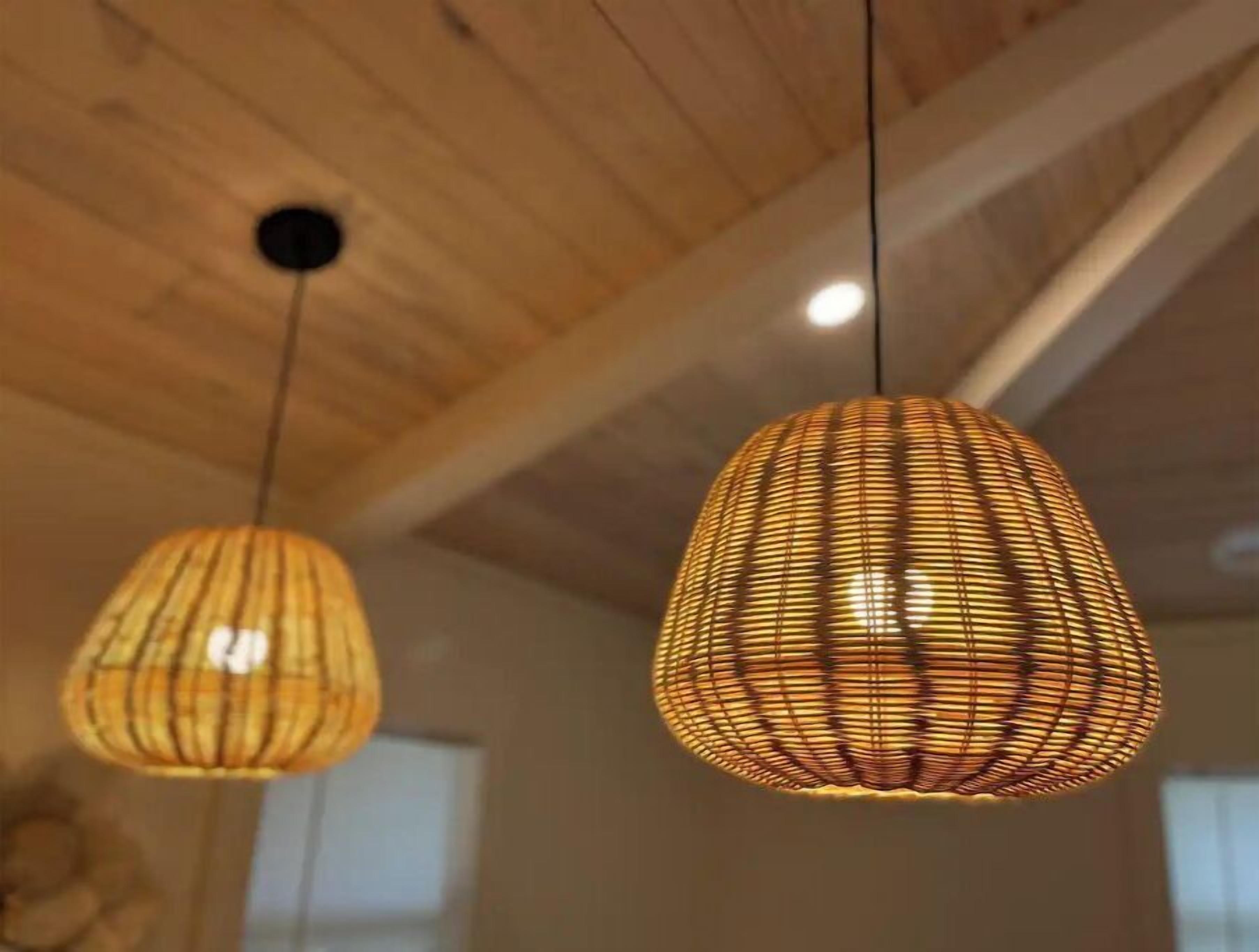 Two hanging pendant lights with a woven design, suspended from a wooden ceiling.