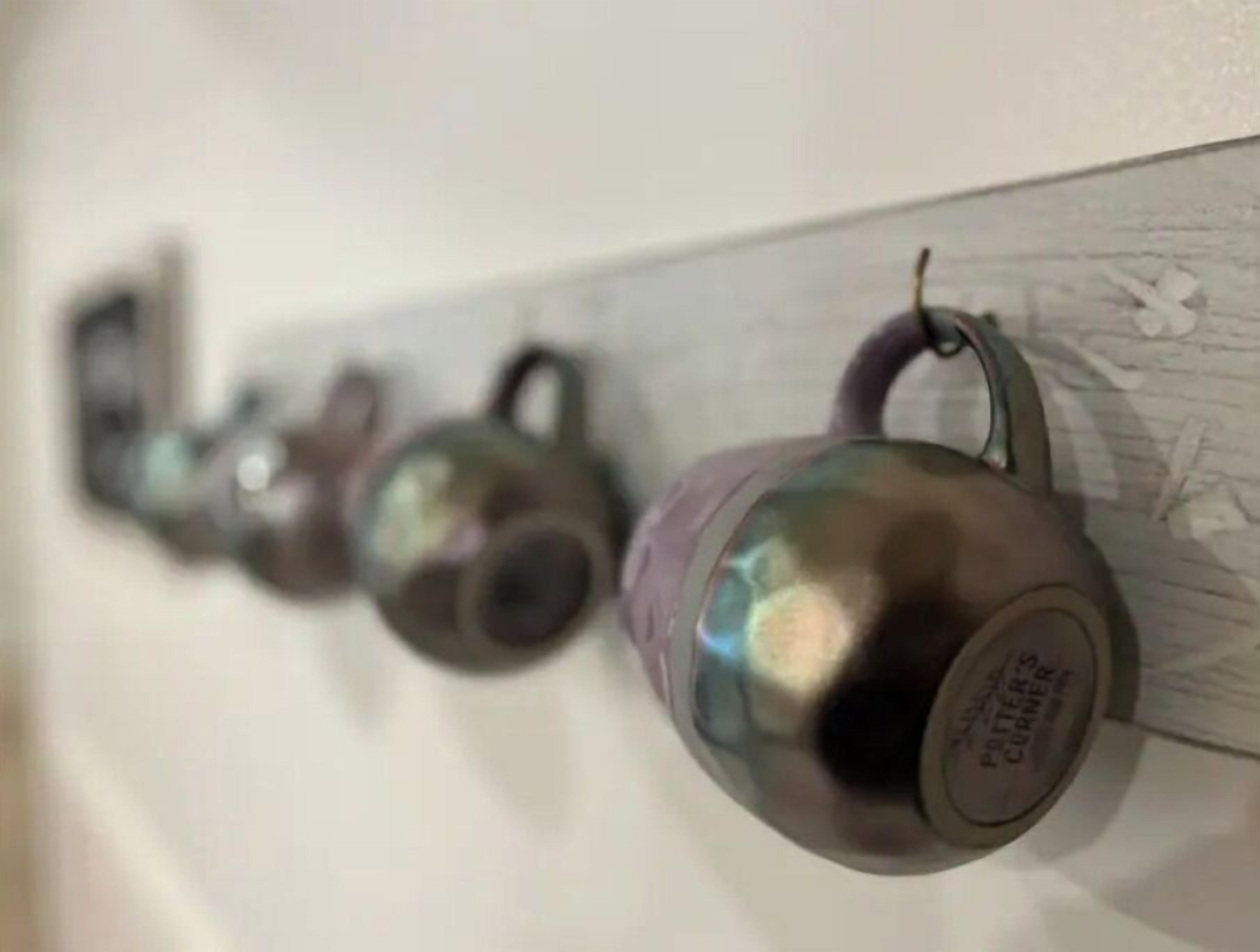 Una hilera de tazas de cerámica colgadas en una pared.