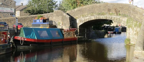 A canal with boats docked under a stone bridge.
