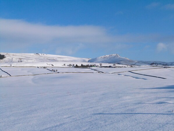 Un paysage enneigé, avec des champs et des collines à l’horizon.