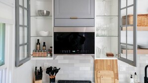 Una cocina moderna con armarios grises, una campana extractora negra y diversos utensilios de cocina.