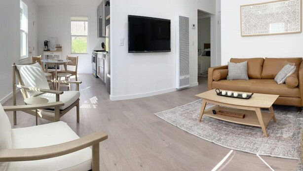 Una sala de estar moderna con un sofá beige, una mesa de centro y un televisor montado en la pared.
