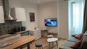 A modern living room with a sofa, a dining table, and a kitchen area. - Charming studio downtown Ajaccio (Ajaccio)