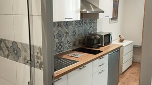 A modern kitchen with white cabinets, a stainless steel range hood, a microwave, and a dishwasher. - Charming studio downtown Ajaccio (Ajaccio)