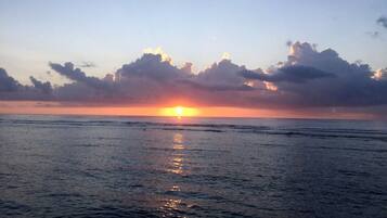 Un coucher de soleil sur une mer calme, avec des nuages dans le ciel.