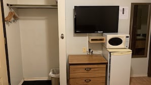 Ein kompakter Raum mit Fernseher, Mikrowelle, einem kleinen Holzkasten und einer Tür zu einem weiteren Raum.