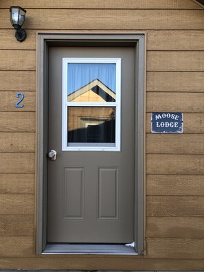 A brown door with a window, a number '2' sign, and a 'Moose Lodge' sign on a wooden wall. - The Moose Lodge (Clark)