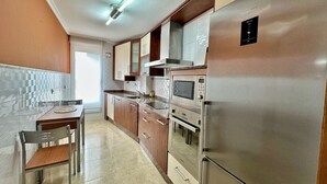 Una cocina moderna con electrodomésticos de acero inoxidable, armarios de madera y salpicadero de azulejos.
