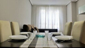 Comedor con una mesa lista para cuatro, con platos, vasos y un cuenco decorativo.
