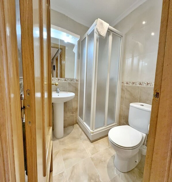 A bathroom with a shower enclosure, toilet, and sink. - Apto céntrico con garaje - Abad Paterno 3008 (Santoña)
