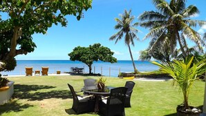 A patio with outdoor furniture overlooking a beach. - Merizo Seaside B&B - Unit 2 Coral Suite (Tasi Merizo)