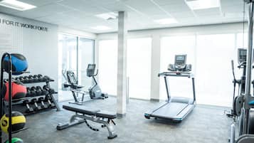 A gym with exercise equipment, a bench, dumbbells, and a treadmill.