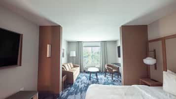 Una habitación de hotel con una cama, un escritorio, una silla, un televisor y una ventana con cortinas.