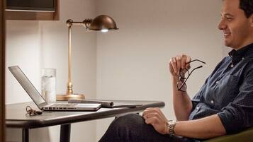 A man sitting at a desk with a laptop, glasses, and a watch.