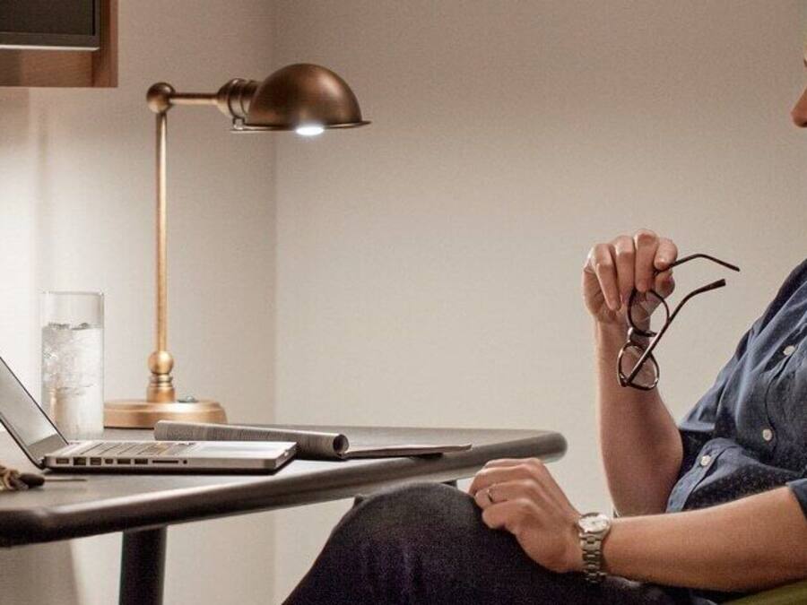 A man sitting at a desk with a laptop, glasses, and a watch.