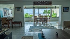 A spacious living room with a large dining area, a television, and a view of the ocean. - Merizo Seaside B&B - Unit 3 Ocean Villa (Tasi Merizo)