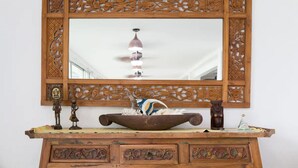 A wooden vanity with intricate carvings, a mirror, and a decorative bowl. - Merizo Seaside B&B - Unit 3 Ocean Villa (Tasi Merizo)