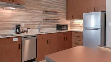 A modern kitchen with stainless steel appliances, wooden cabinets, and a marble backsplash.