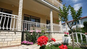 A two-story building with a balcony, stone facade, and a garden with red roses. - Anica  A4 -  Apartment with two bedrooms (Baška)