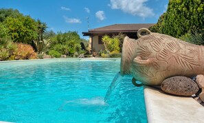 Una piscina con una escultura de piedra.