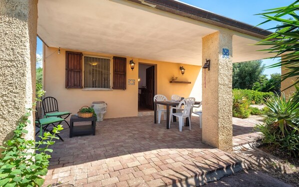 Un patio techado con piso de ladrillo, mobiliario exterior y vistas a zonas verdes.