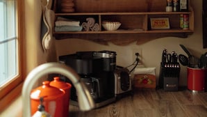 A kitchen with wooden shelves, a sink, and various kitchen items.