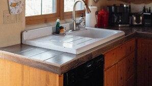 A kitchen with wooden cabinets, a white sink, and a window above the sink.
