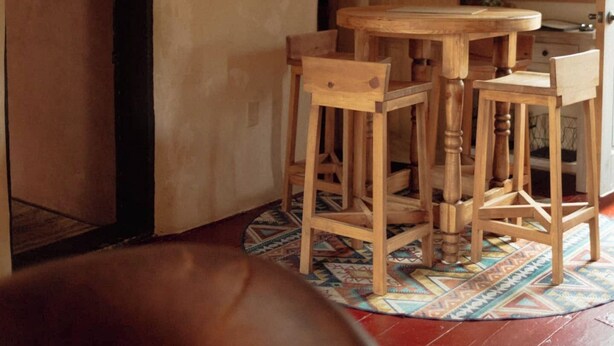 A dining area with a wooden table and chairs, a hanging lantern, and a painting on the wall.