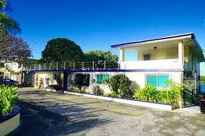 A two-story building with a blue and white facade, a covered walkway, and a parking area with yellow lines.
