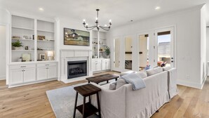 Una sala moderna con chimenea, muebles blancos y un sofá grande.