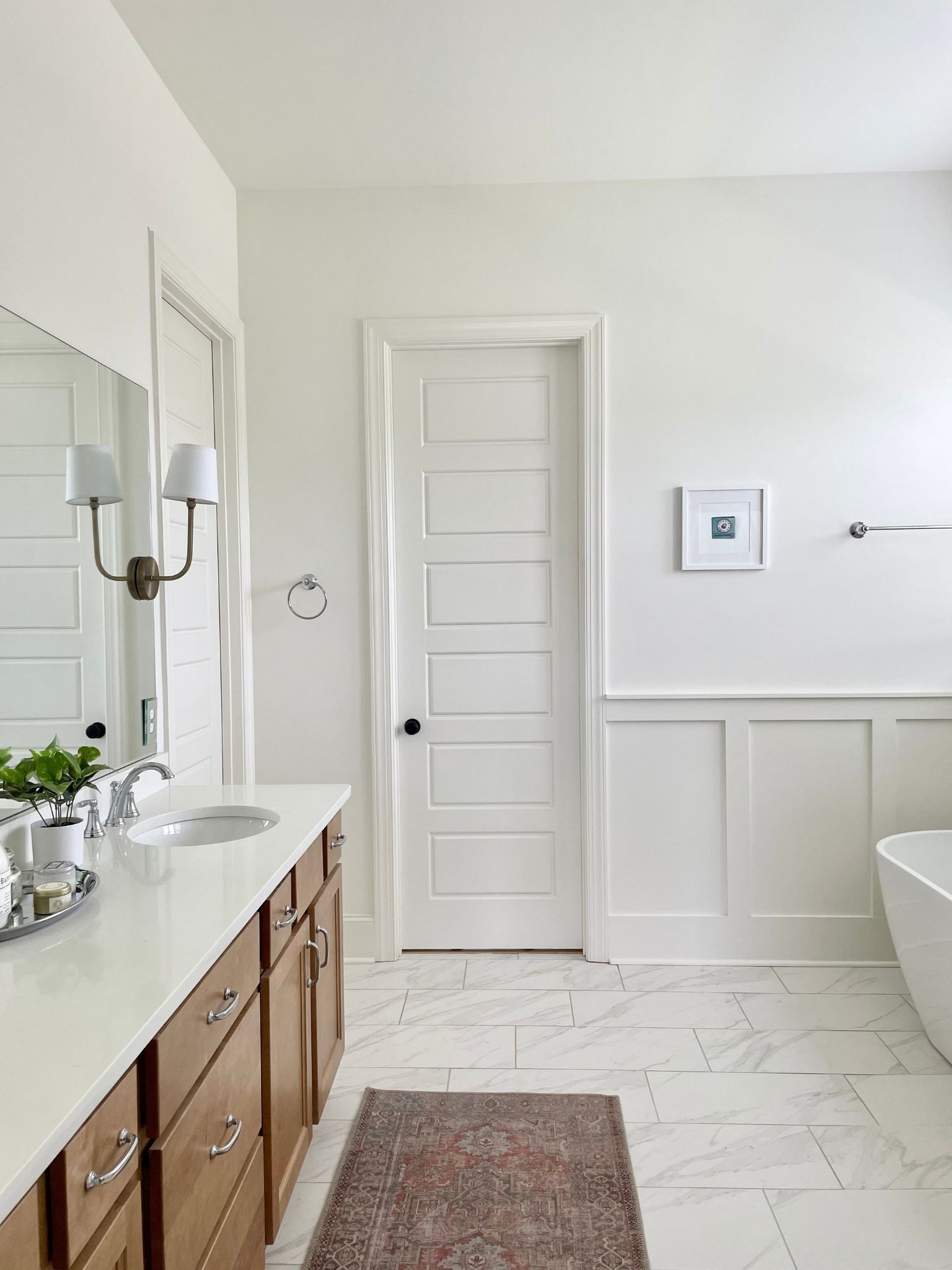 Une salle de bain moderne avec un meuble-lavabo blanc, un grand miroir, un évier et une baignoire.