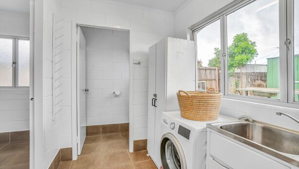 A laundry room with a washing machine, a sink, and a basket on the machine. - 13 Indigo Avenue - 'Indigo Sands' - Rainbow Beach. Beds made for arrival. Close to beach (Rainbow Beach)