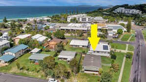 An aerial view of a residential area with houses, a road, and a view of the ocean. - 13 Indigo Avenue - 'Indigo Sands' - Rainbow Beach. Beds made for arrival. Close to beach (Rainbow Beach)