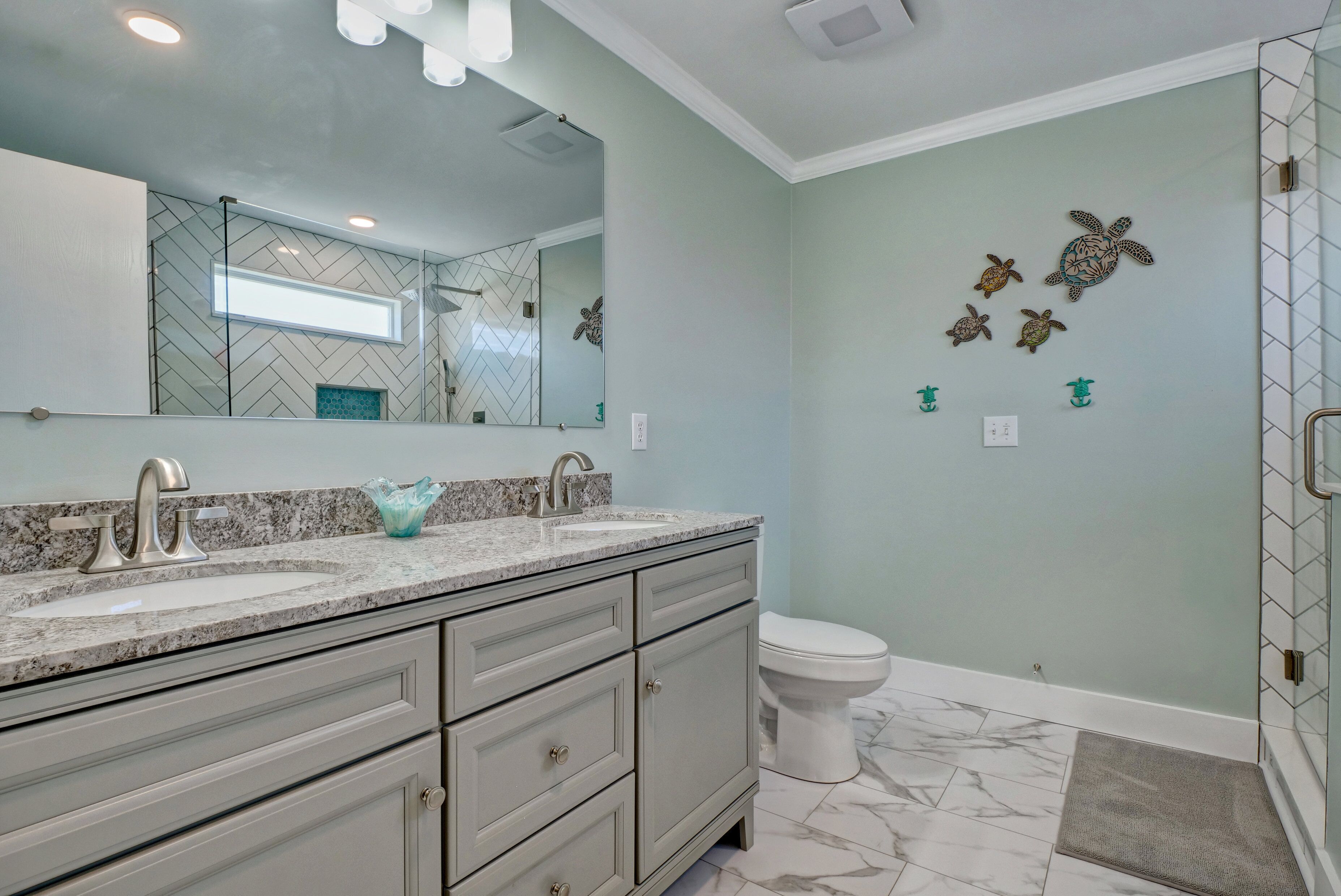 A bathroom with two sinks, a large mirror, and a toilet.