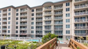 A multi-story residential building with balconies, a swimming pool, and a wooden deck.