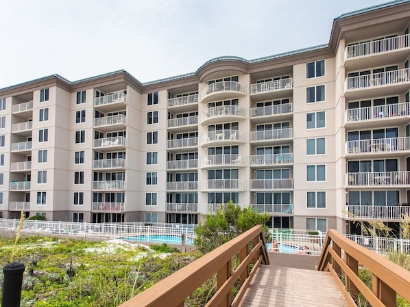 Un immeuble résidentiel à plusieurs étages, doté de balcons, d’une piscine et d’une terrasse en bois.