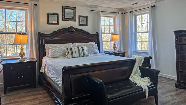 A bedroom with a large bed, two bedside tables, a chair, and a dresser.