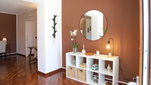 A hallway with a white console table, a round mirror, wicker baskets, and a small plant.