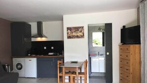 Un espacio habitable compacto con kitchenette, comedor y televisor.