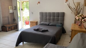 Un dormitorio con una cama grande, una mesita de noche de madera, una maleta y vistas al exterior.