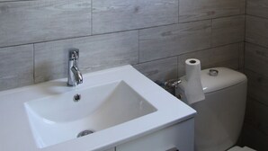 Un baño con lavamanos blanco, un espejo y un inodoro.