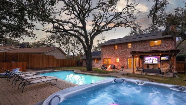 A backyard with a swimming pool, hot tub, and a brick house with outdoor seating. - Heated Pool-HotTub-Game Room-Fire Pit-Big Backyard (San Antonio)