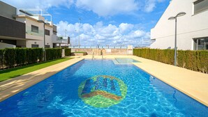 Une piscine dotée d’un bassin aux eaux d’un bleu limpide, entourée de bâtiments modernes et d’une pelouse bien entretenue.
