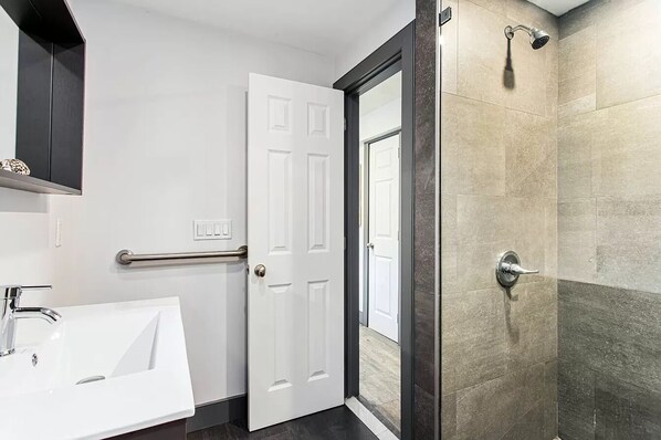 A modern bathroom with a white bathtub, a white door, and a shower area with a glass door.