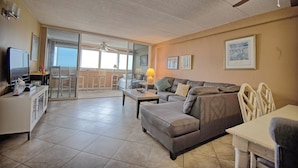 A spacious living room with a sofa, a coffee table, and a TV. There is a balcony with a view. - 🏖 *Ocean *Ocean *Ocean* 🏖 Beautiful Condo!! (Ocean City)