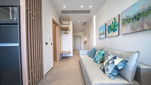 A modern hallway with a sofa, artwork, and a kitchen area. - Oleas Suite Venus & Private Pool (Heraklion)